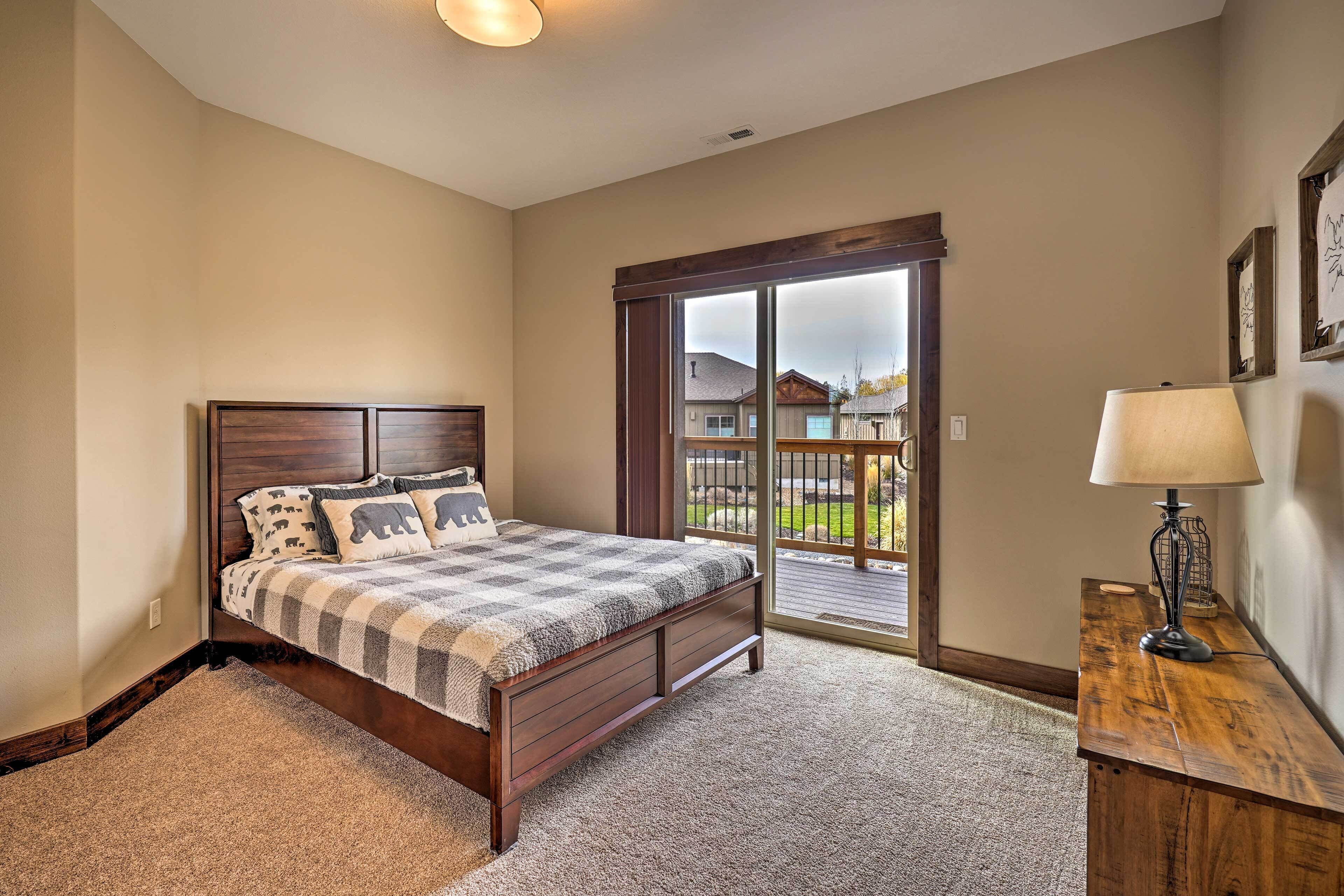 A bedroom with a bed, a wooden nightstand, a lamp, and a view of the outside through a glass door.