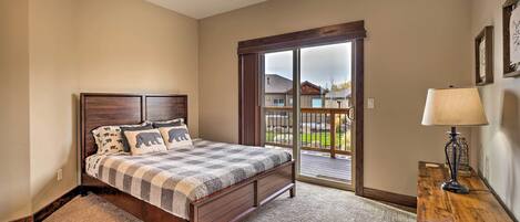 A bedroom with a bed, a wooden nightstand, a lamp, and a view of the outside through a glass door.