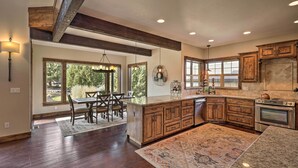 A spacious kitchen with wooden cabinets, a large island, and a dining area with a table and chairs. - Modern Eagle Crest Escape w/ Patio & 2 Balconies! (Redmond)