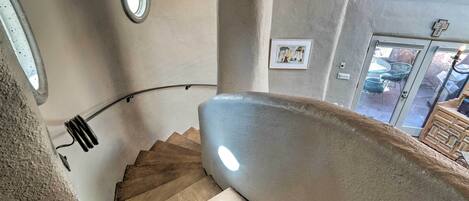 A spiral staircase with a handrail, a light fixture, and a framed picture on the wall.