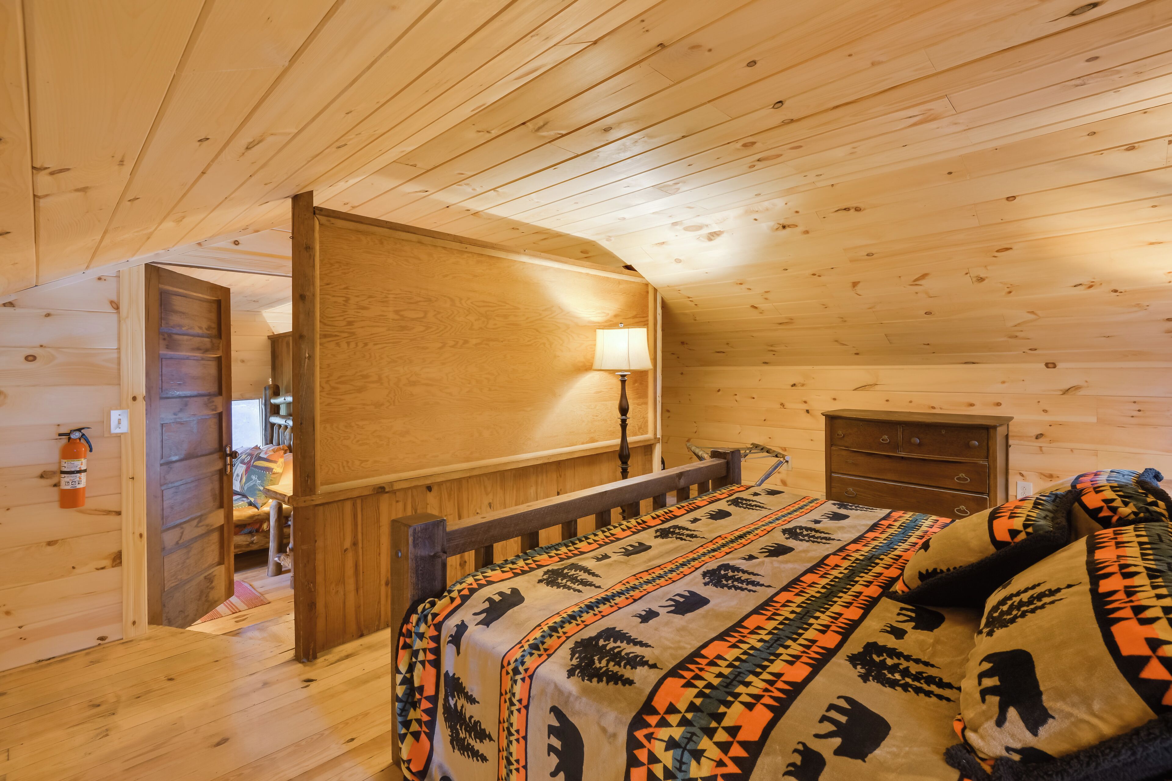 Une chambre dans une cabane en bois, avec un lit, une table de chevet, une lampe et une commode.