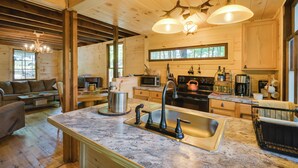 Eine geräumige Küche mit Granit-Arbeitsplatten, einer Spüle und einem Herd. Es gibt einen Essbereich mit Tisch und Stühlen sowie ein Wohnzimmer mit einer Couch und einem Kamin.