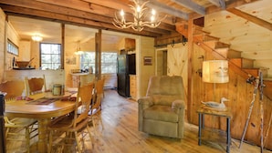 Ein Holzinterieur mit Esstisch, Stühlen, einer Couch, einer Lampe und einer Treppe.