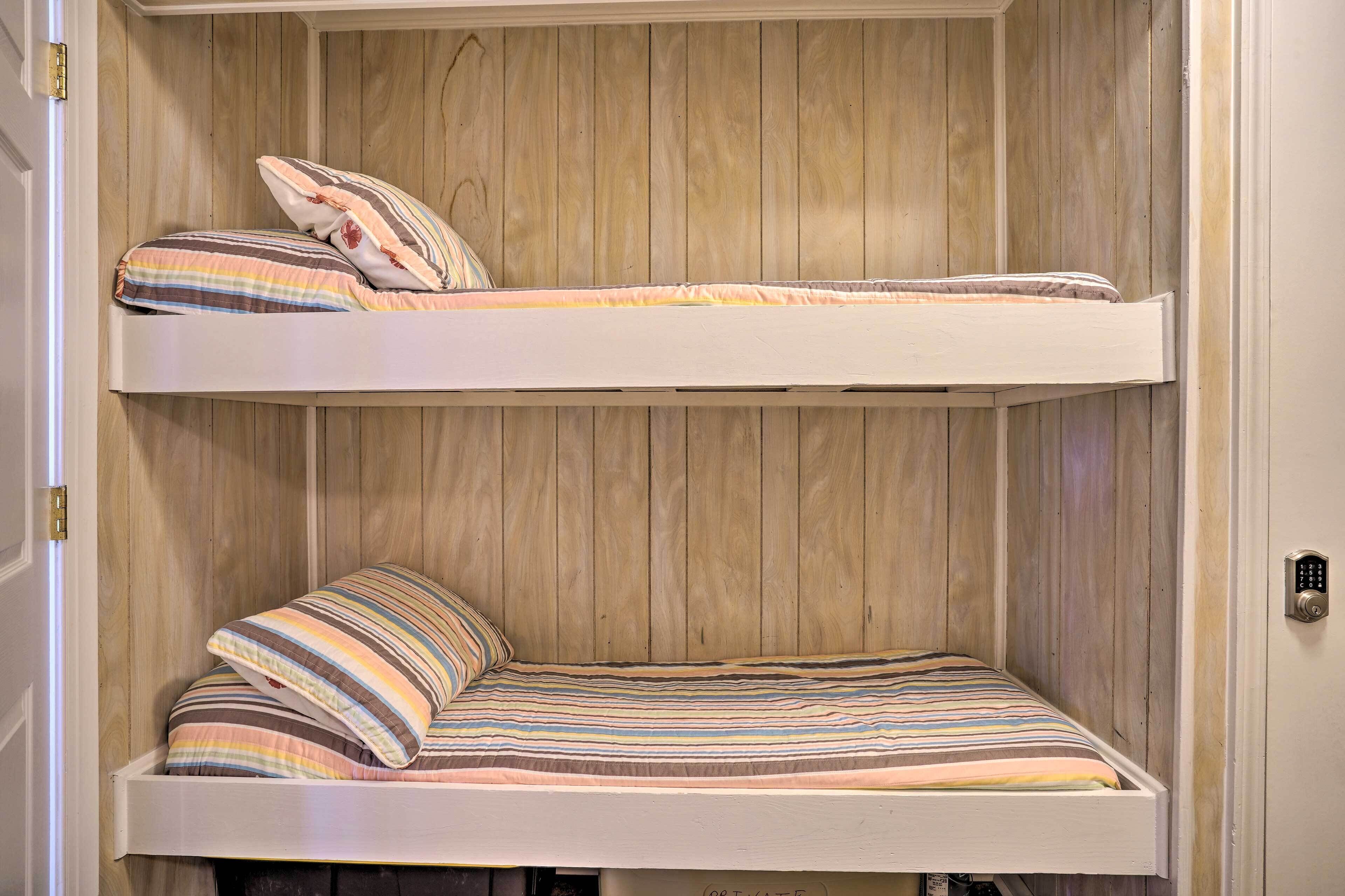 Een stapelbed met strepen beddengoed en een houten paneelwand.