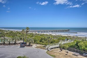 A beach view with a pier, parking area, and a truck. - Beachfront Isle of Palms Condo w/ Balcony & Pool! (Isle of Palms)