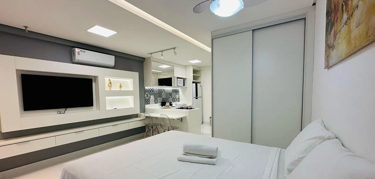 Una habitación de hotel moderna con cama, televisor, baño con espejo y armario.
