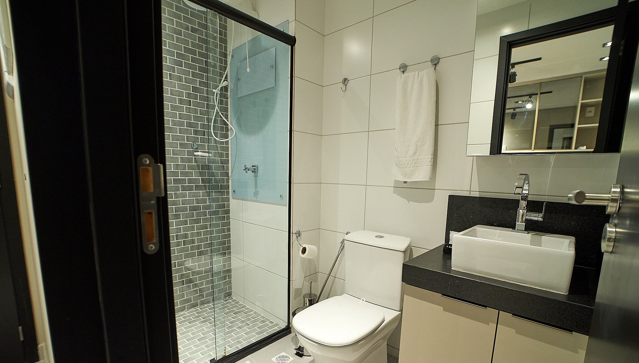 A modern bathroom with a glass-enclosed shower, a white toilet, and a black countertop with a sink.