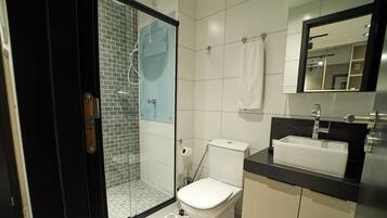 A modern bathroom with a glass-enclosed shower, a white toilet, and a black countertop with a sink.