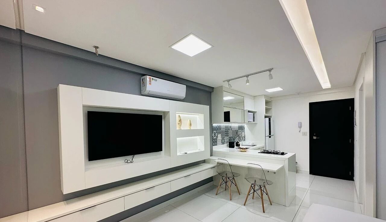 Uma cozinha moderna com televisão integrada, uma ilha central e um espelho grande acima da pia.