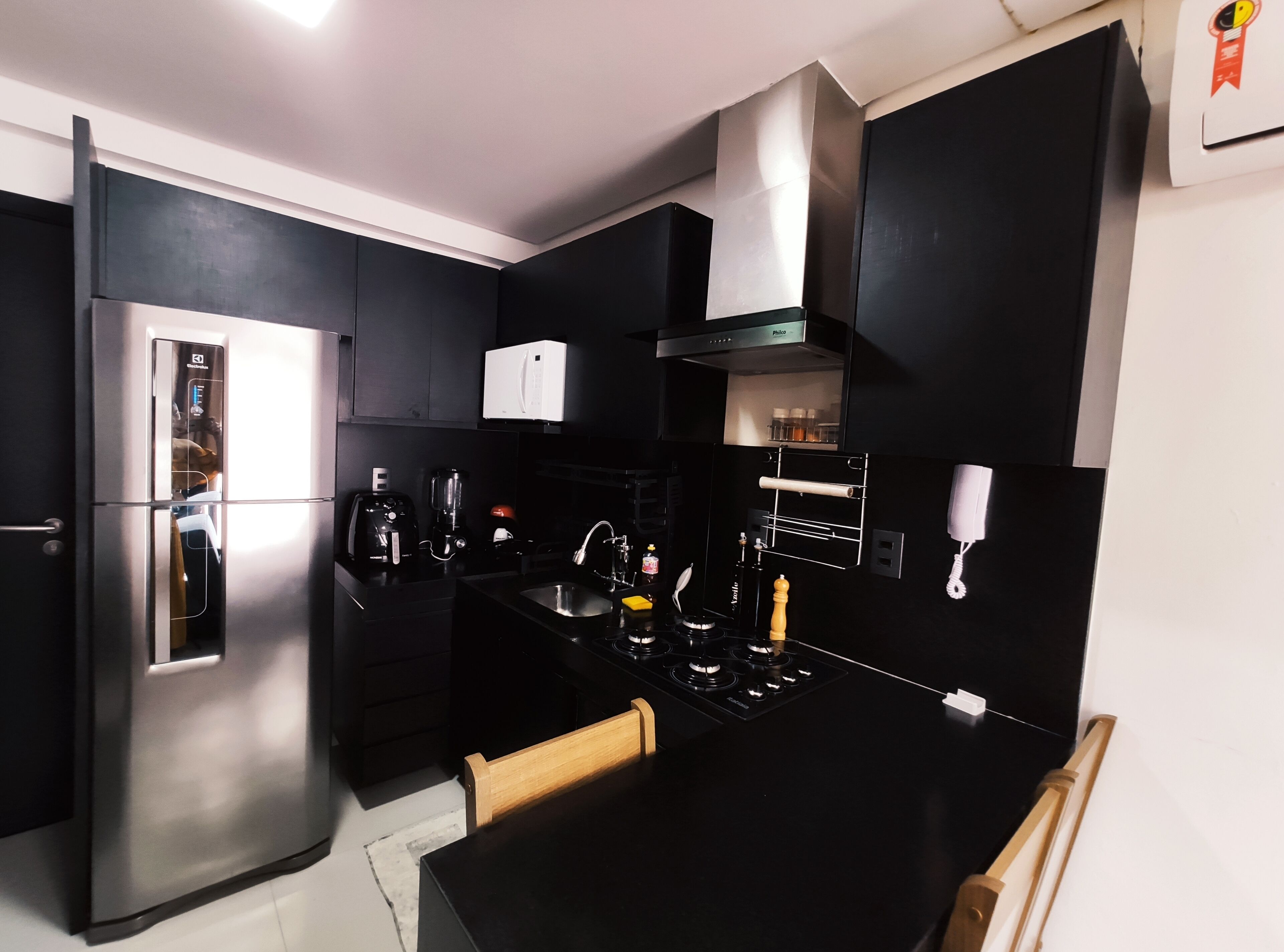 A modern kitchen with black cabinetry, stainless steel appliances, and a black countertop.