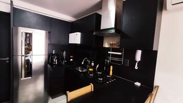 A modern kitchen with black cabinetry, stainless steel appliances, and a black countertop.