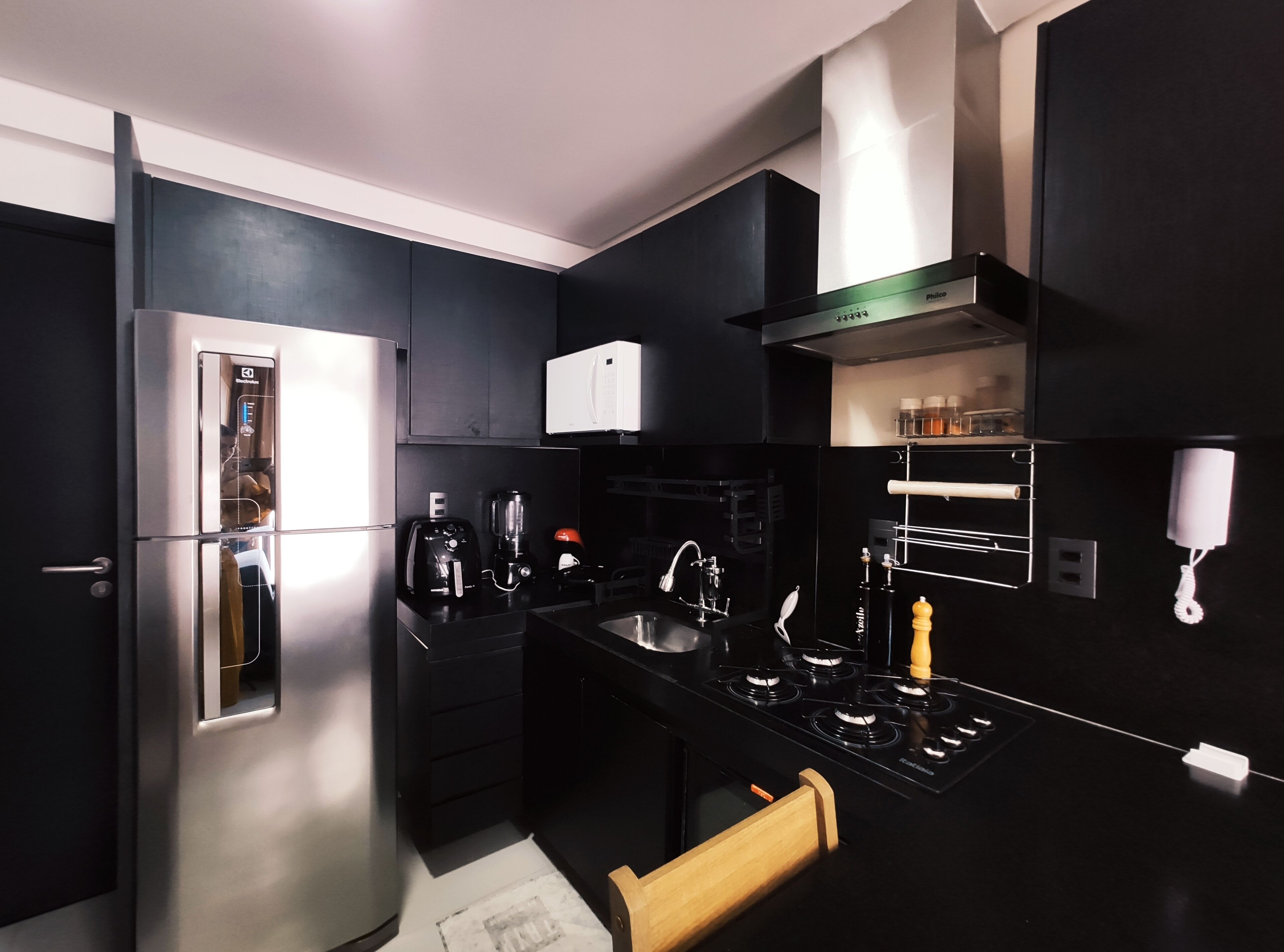 A modern kitchen with a stainless steel refrigerator, a coffee maker, a microwave, and a gas stove.