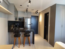 Una cucina moderna con isola centrale, due sgabelli da bar, un frigorifero e un forno a microonde.