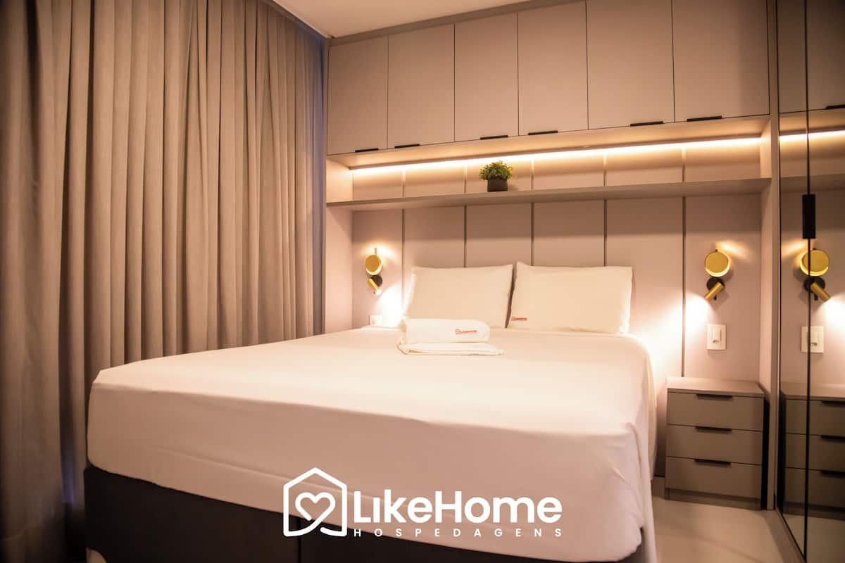 Une chambre à coucher moderne avec un grand lit, des tables de chevet et une tête de lit dotée d’un éclairage intégré.