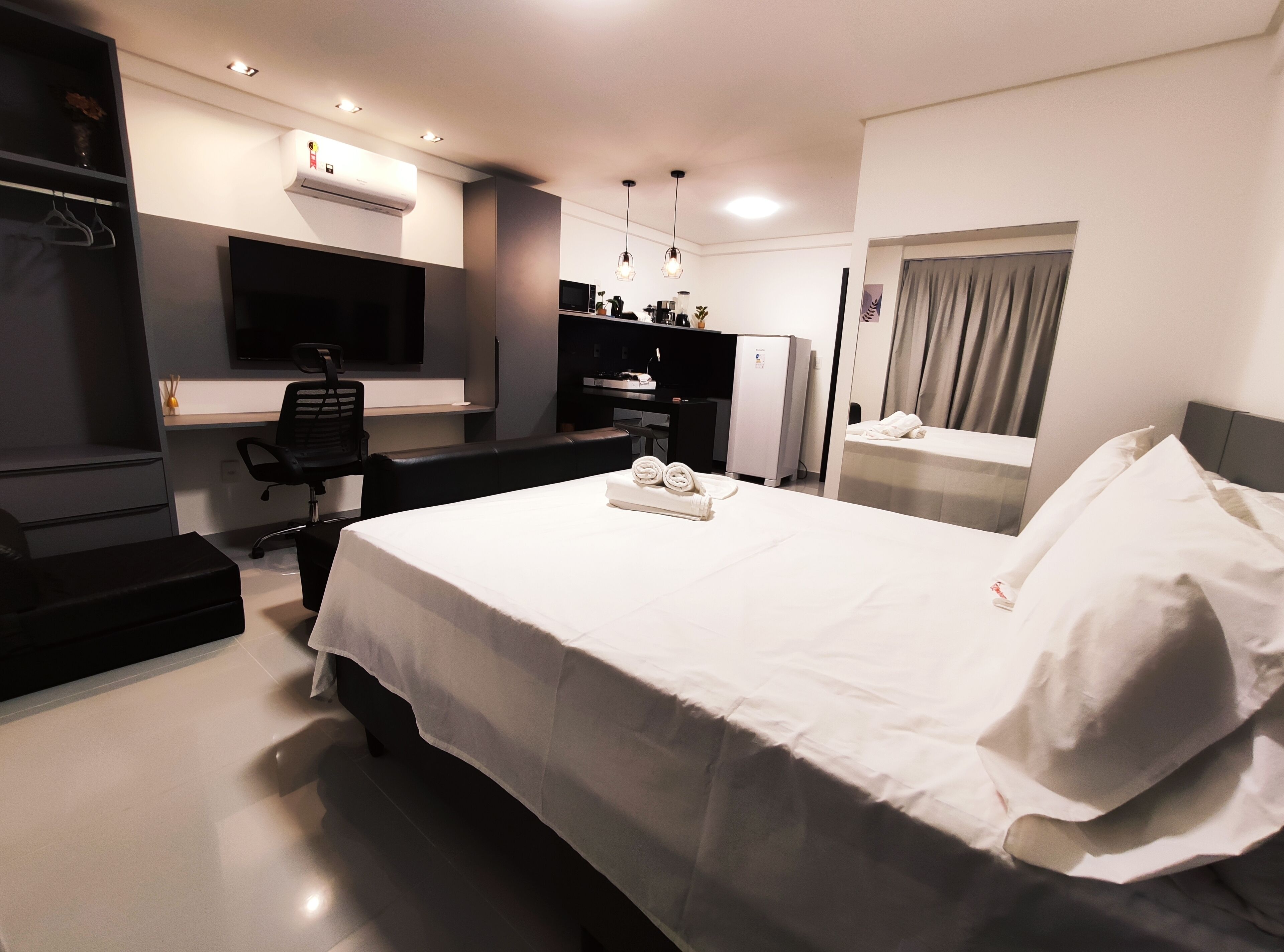 Ein modernes Hotelzimmer mit einem großen Bett, einem Schreibtisch, einem Flachbildfernseher, einer Minikühlschrank und einer eingebauten Klimaanlage.