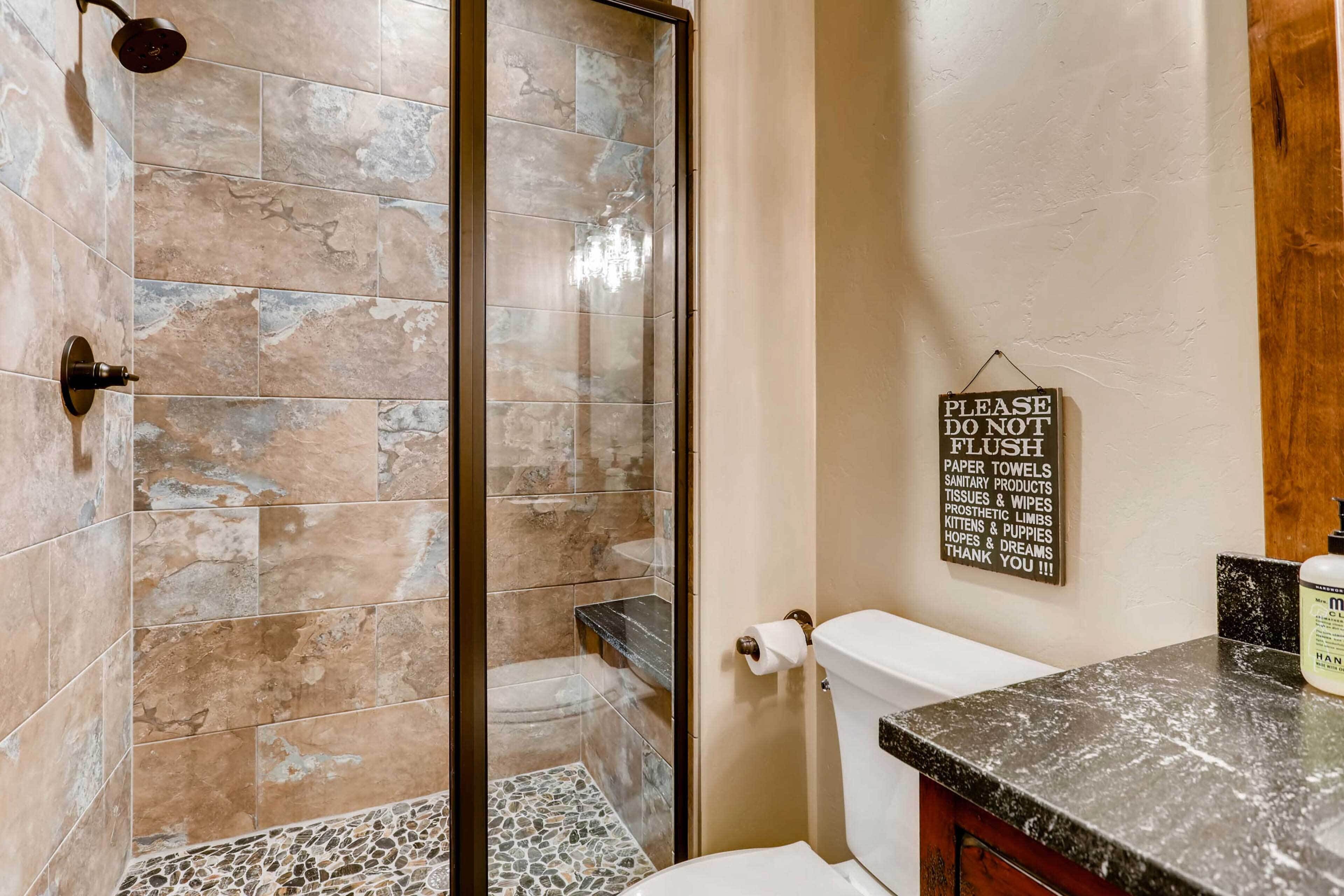 A bathroom with a shower, toilet, and a sign on the wall.