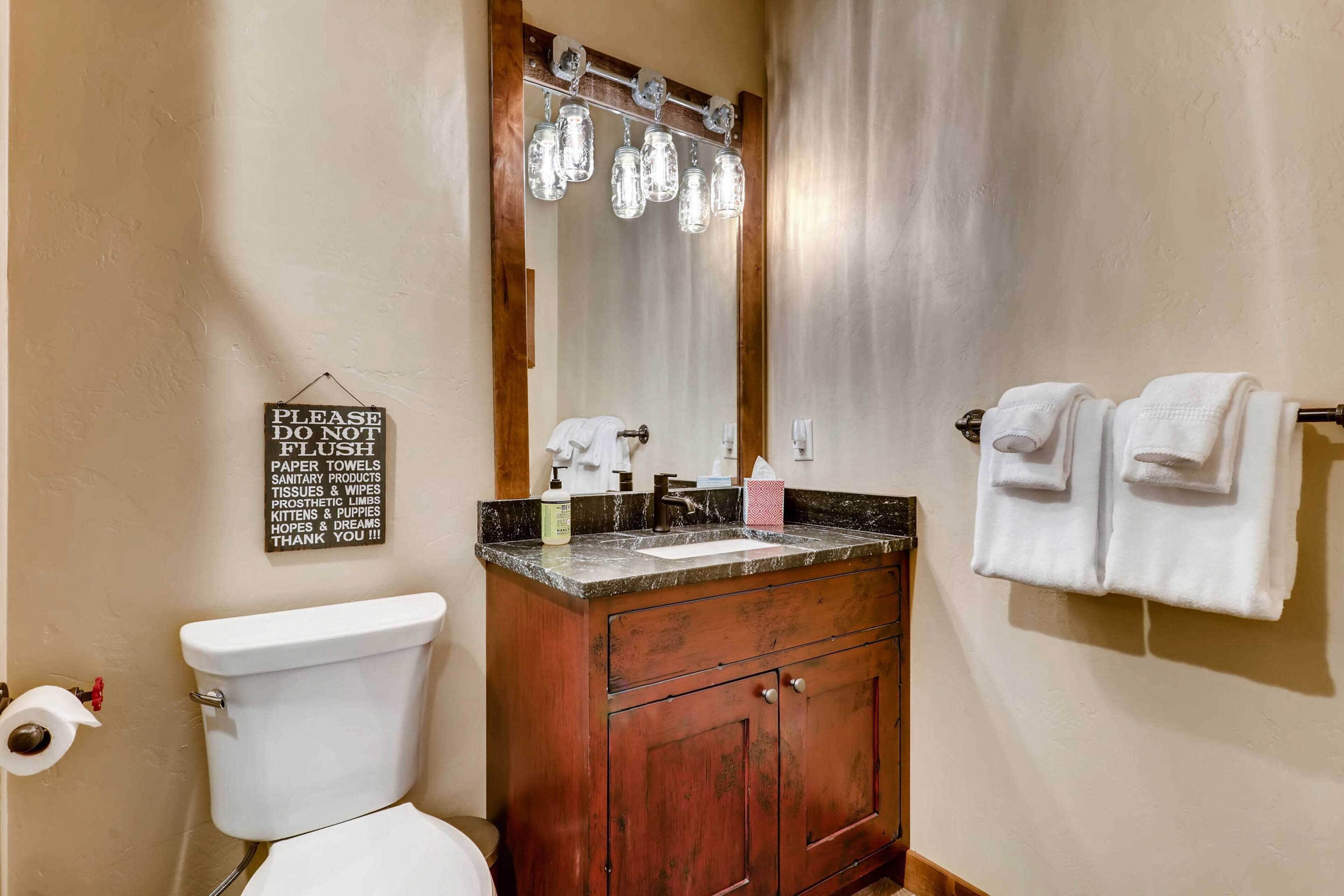 Une salle de bain comprenant des toilettes, un lavabo, un meuble-lavabo et un miroir.