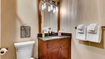 Une salle de bain comprenant des toilettes, un lavabo, un meuble-lavabo et un miroir.