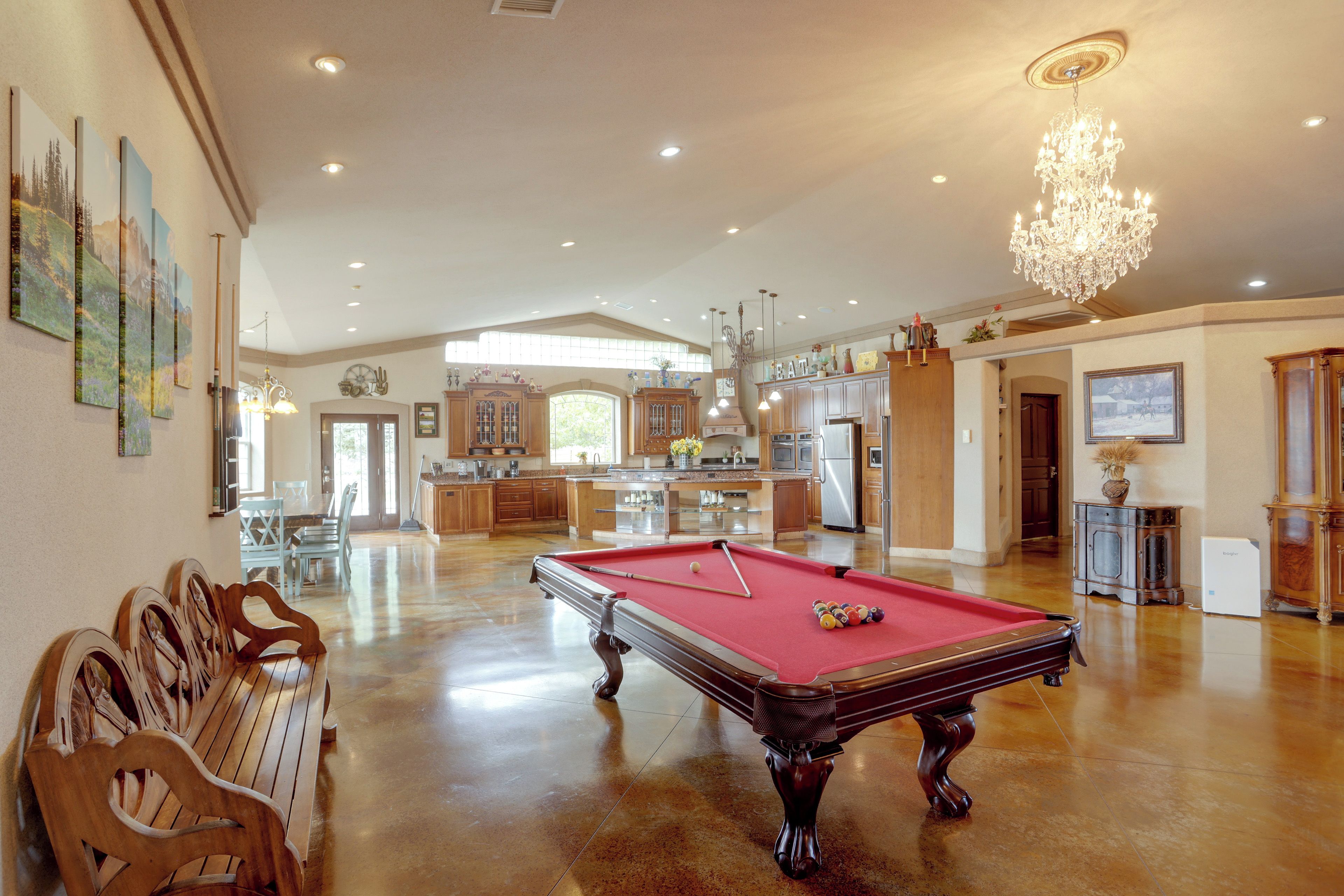 Amplia sala de estar con mesa de billar, muebles de madera y un candelabro.