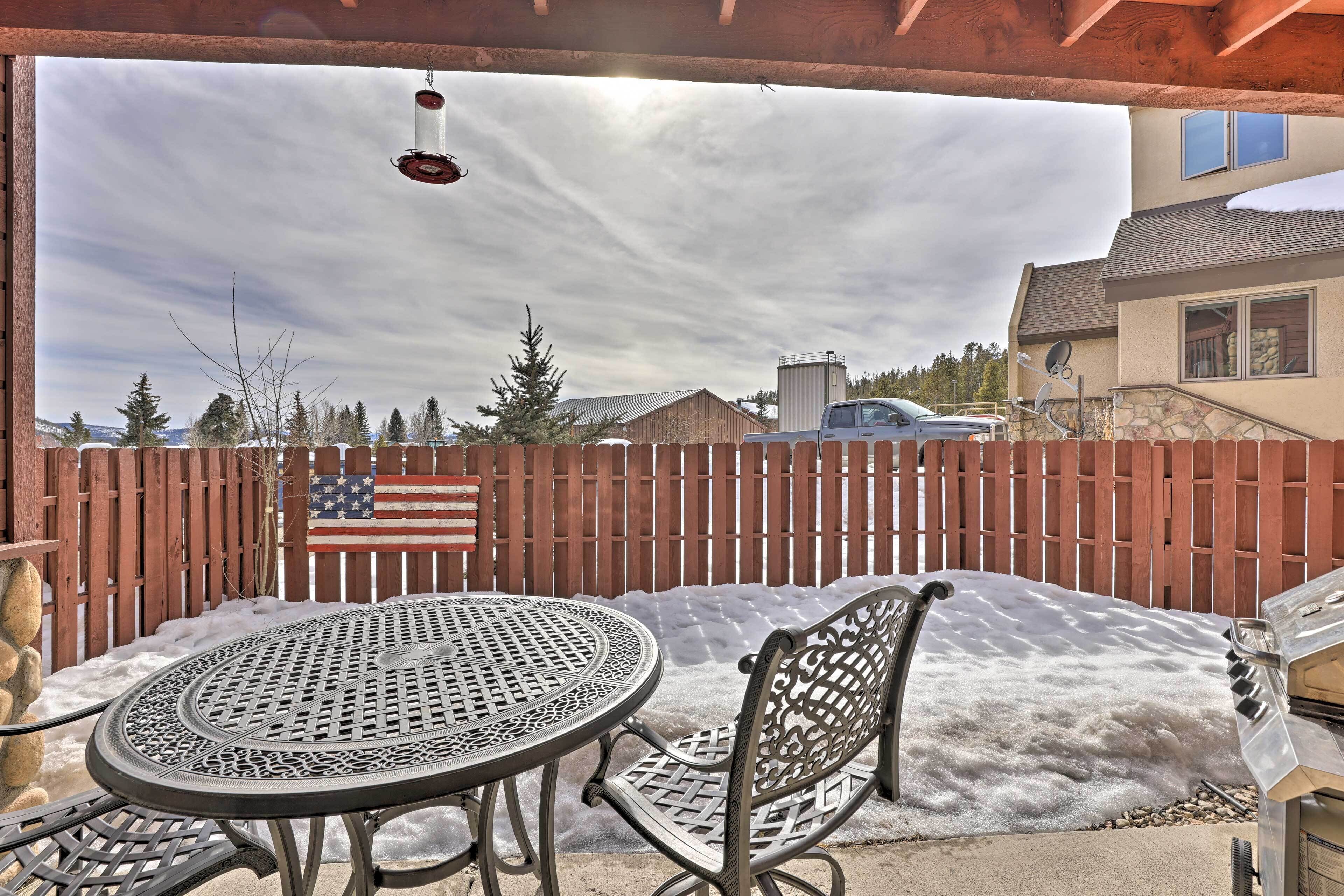 A patio with a metal table and chairs, a wooden fence, and an American flag.