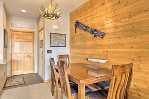 Un comedor de madera con una mesa y sillas, un soporte para esquíes montado en la pared y un letrero de bienvenida.