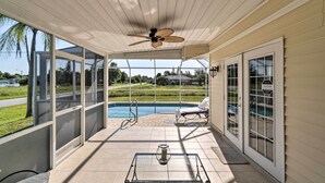 A covered patio with a ceiling fan, a glass door leading to a swimming pool, and a lounge chair. - Charming Port Charlotte Home w/ Lanai & Pool! (Port Charlotte)