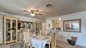 A dining room with a round table set for six, surrounded by six chairs. There is a ceiling fan above the table and a large mirror on the wall. - Charming Port Charlotte Home w/ Lanai & Pool! (Port Charlotte)