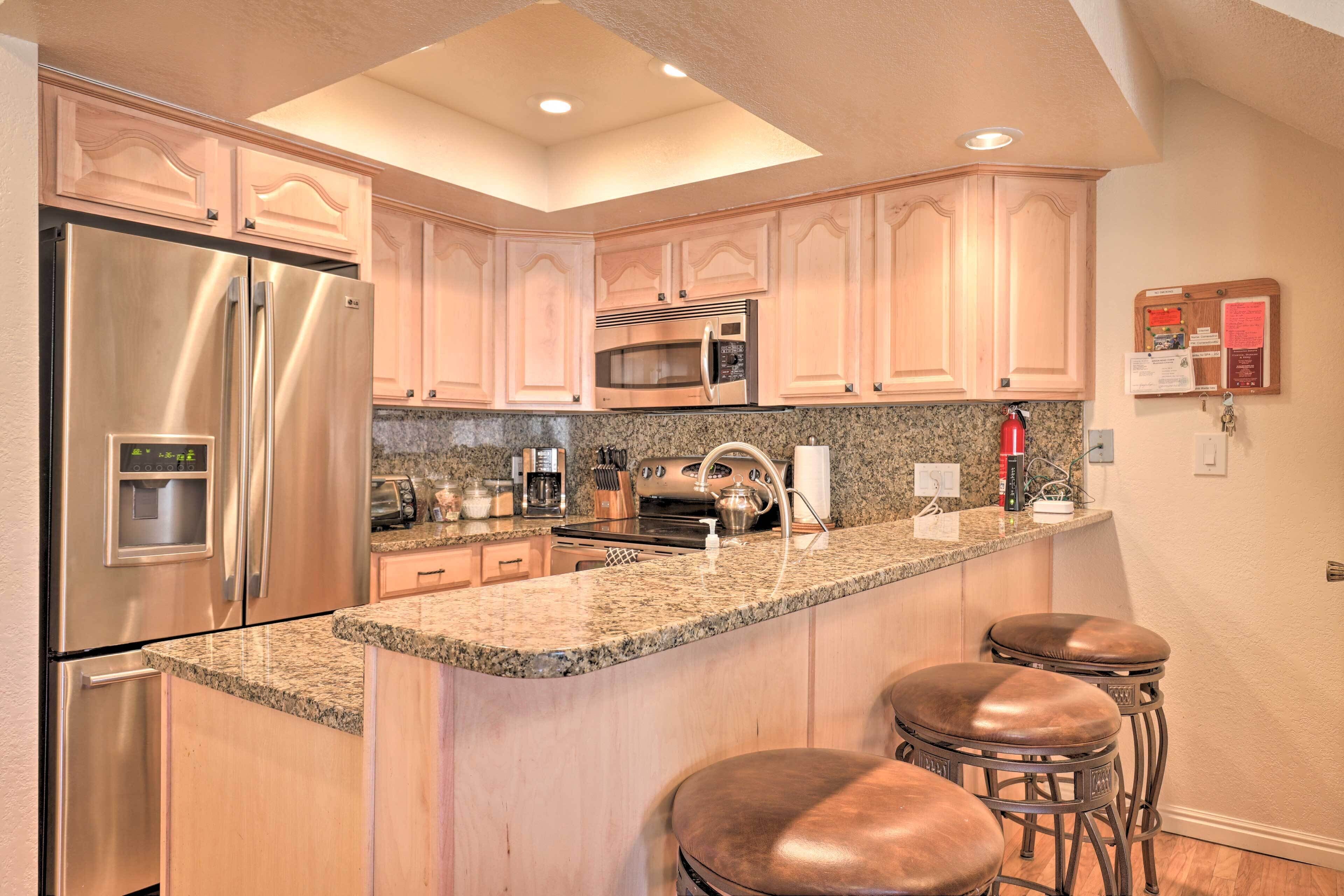 A kitchen with stainless steel appliances, granite countertops, and wooden cabinets.