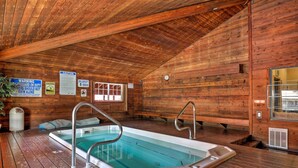 Une cabane en bois dotée d’un bain à remous, de murs en bois et d’un plafond avec des poutres apparentes.