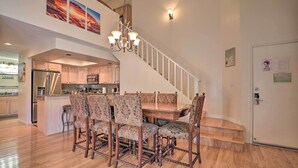 Une salle à manger spacieuse, avec une table en bois et des chaises à motifs, un lustre et un escalier menant à un niveau supérieur.