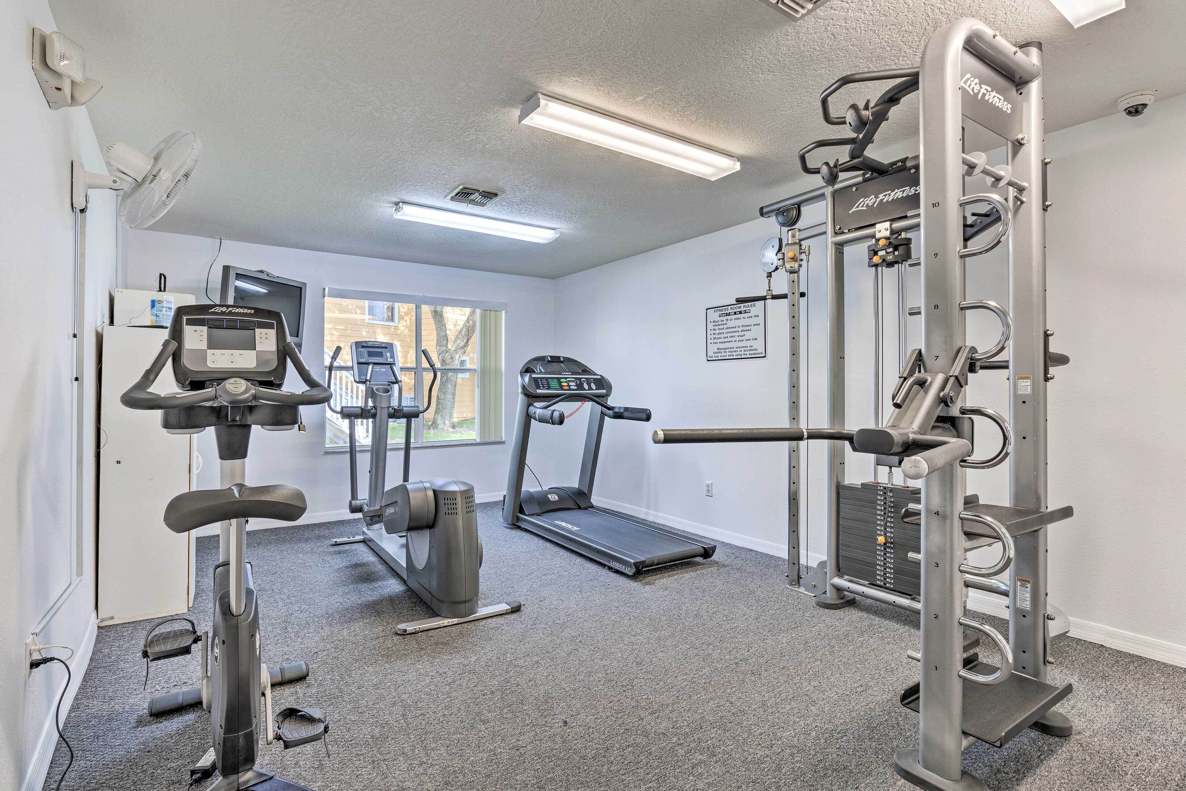 A gym with cardio equipment, a treadmill, and a weightlifting station.