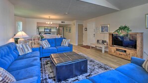 A living room with blue sofas, a coffee table, and a TV stand. - Kissimmee Family Home! Community Pool + Playground (Kissimmee)