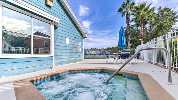 A hot tub with a metal ladder, a blue building, and a white fence. - Kissimmee Family Home! Community Pool + Playground (Kissimmee)