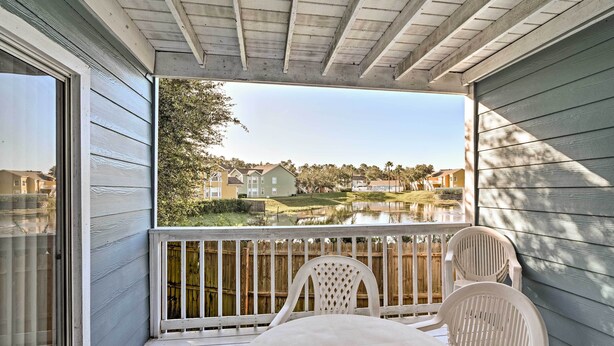 A covered outdoor area with a table and chairs, a view of a lake, and a wooden deck. - Kissimmee Family Home! Community Pool + Playground (Kissimmee)