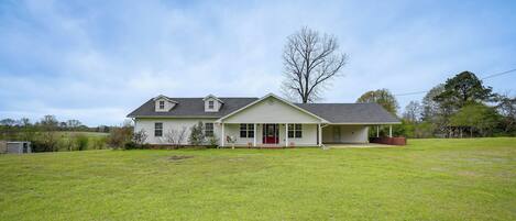 A single-story house with a front porch, a red door, and a well-maintained lawn.