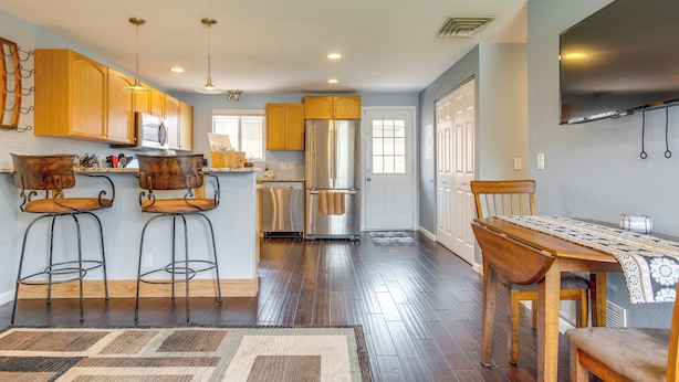 A modern kitchen with wooden cabinets, stainless steel appliances, and a dining area with a table and chairs. - 12 Mi to Denver: Golden Vacation Rental! (Golden)