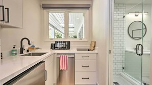 Una cocina compacta con lavavajillas, microondas y ventana sobre el fregadero.