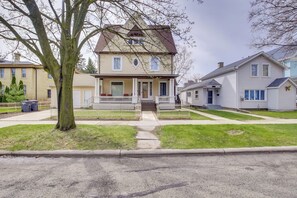 A two-story house with a front porch, a small front yard, and a driveway leading to the garage. - Updated Sheboygan Home w/ Porch < 1 Mi to Beach (Sheboygan)