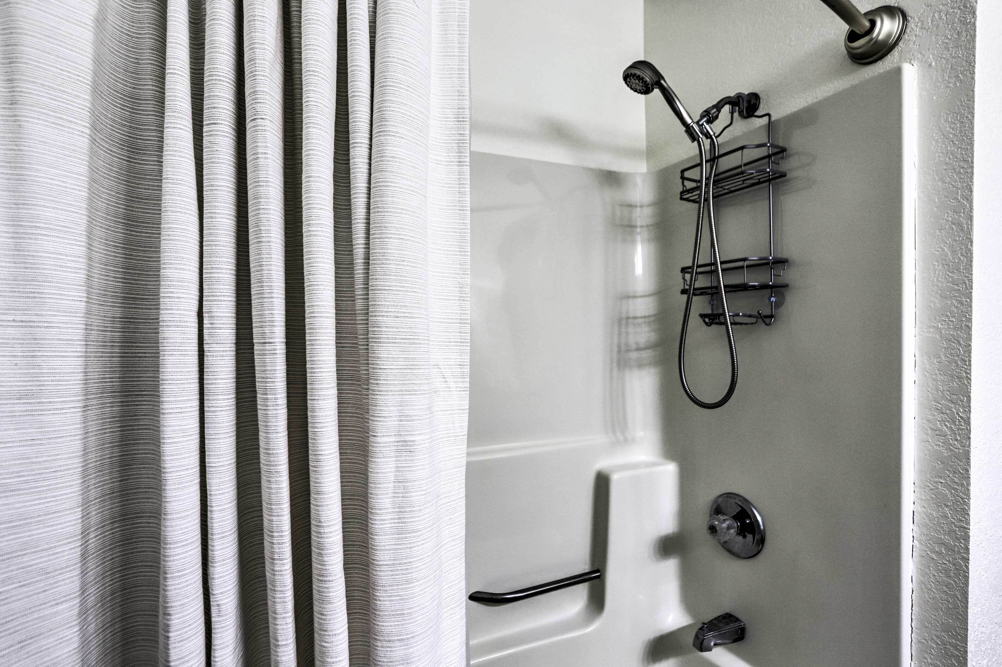 A bathroom with a shower, a towel rack, and a control panel.