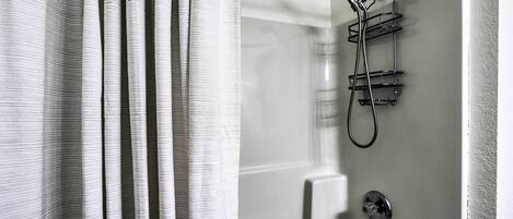 A bathroom with a shower, a towel rack, and a control panel.