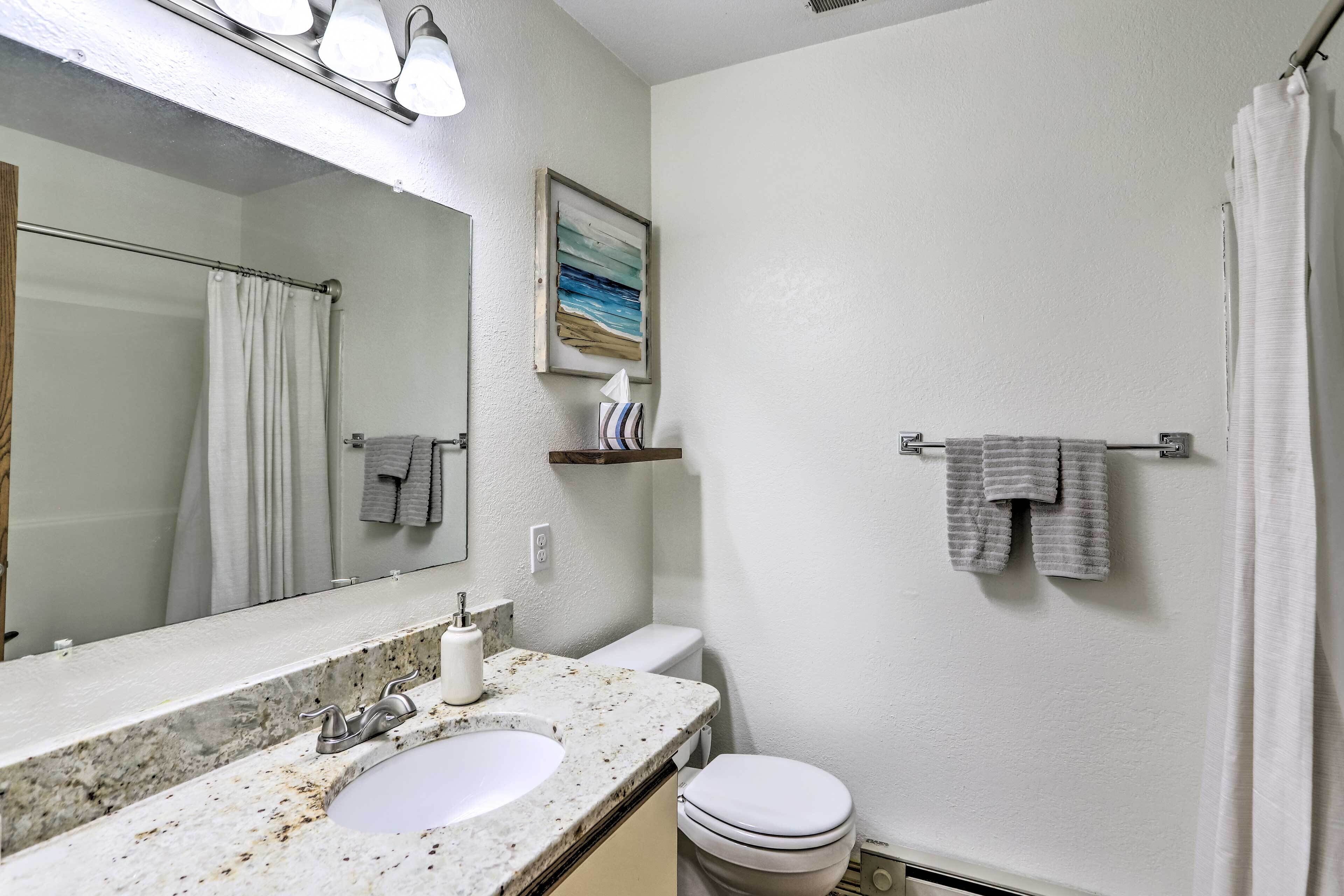 A bathroom with a marble sink, a toilet, a shower curtain, and a towel rack.
