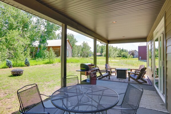 An outdoor patio with a grill, chairs, and a table.