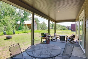 Un patio al aire libre con una parrilla, sillas y una mesa.