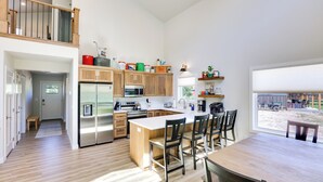 Eine moderne Küche mit Holzausbau, Edelstahlgeräten und einer großen Kochinsel mit Barhocker.