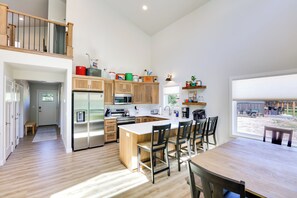 Una cocina moderna con armarios de madera, electrodomésticos de acero inoxidable y una isla grande con taburetes de bar.