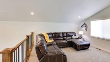 A spacious living room with a sectional sofa, a wooden staircase, and a wall-mounted fish decal.
