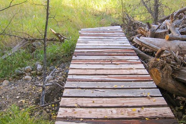 A wooden pathway through a natural setting with rocks and vegetation on either side. - Creek Access + Fire Pit! Red Lodge Family Retreat (Red Lodge)