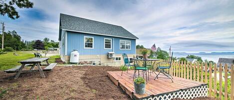 A blue house with a deck, a picnic table, and a view of the ocean.