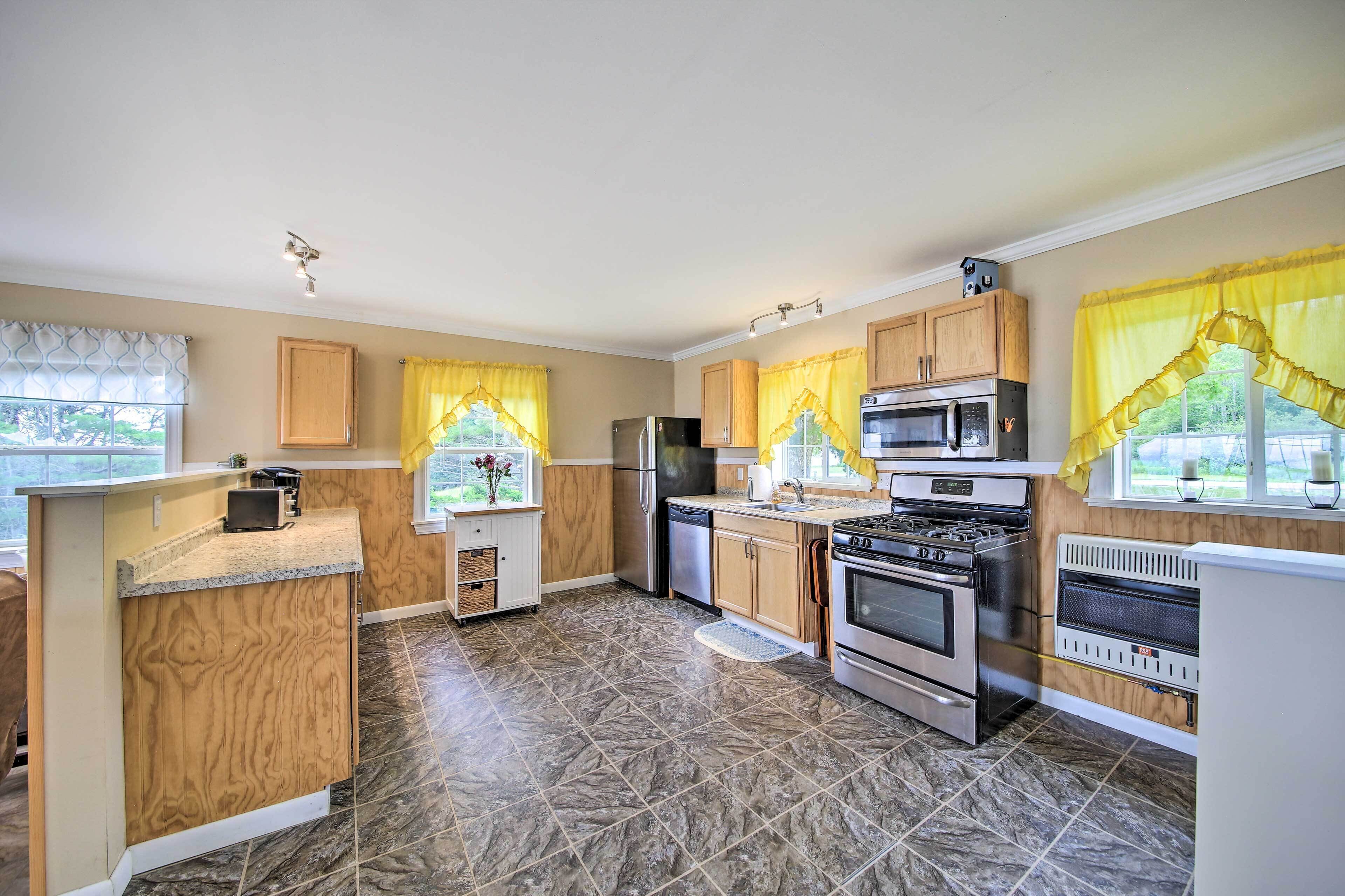 A modern kitchen with granite countertops, stainless steel appliances, and yellow curtains.