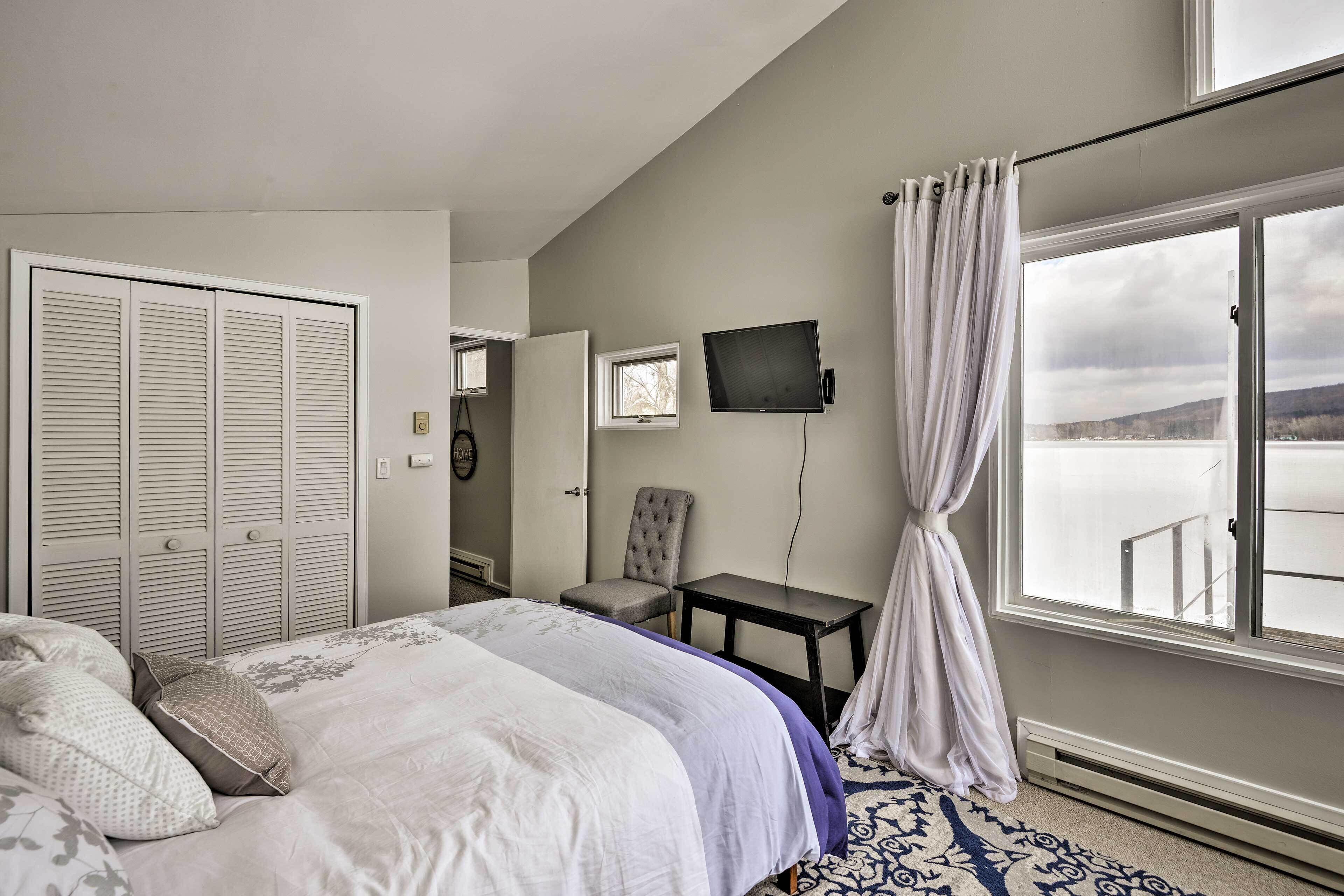 A hotel room with a bed, a chair, a small table, a TV, and a window with a view.